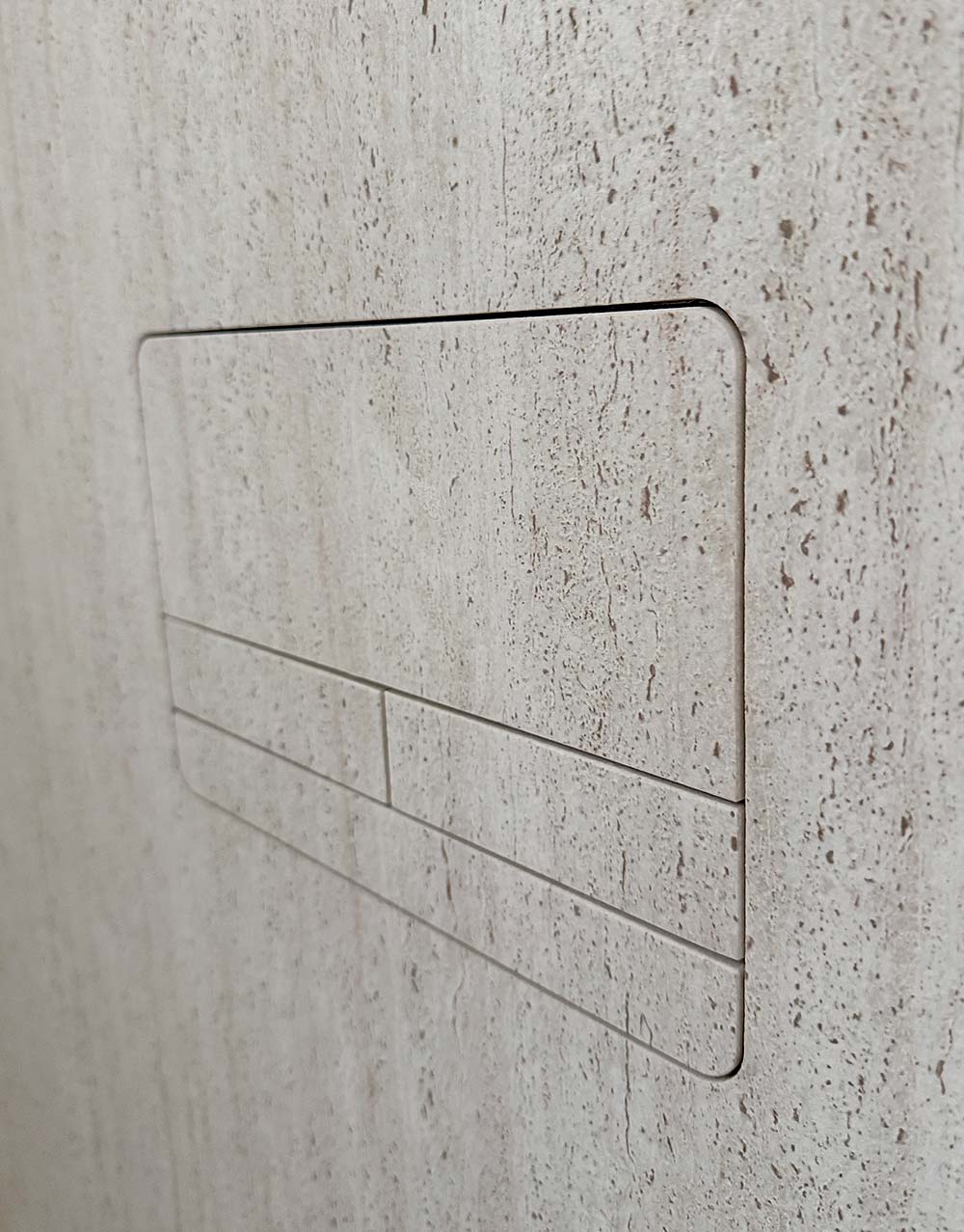 Rahmen mit Schaltern an einer Wand mit beigem, strukturiertem Fliesenmuster.
