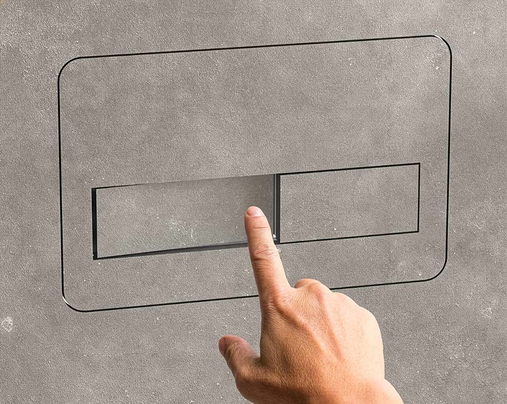 Hand drückt auf die kleinere rechte Taste einer wandmontierten Toilettenspülung mit zwei Tasten.