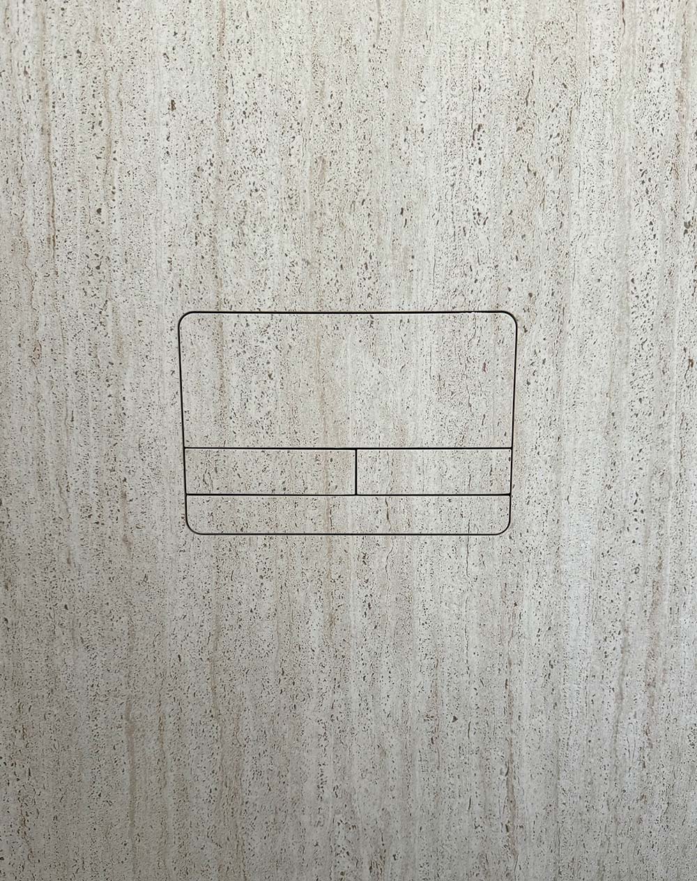 Beige Wand mit integriertem doppelt geteiltem quadratischem Betätigungsfeld für eine Toilette.